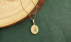 yellow gold oval necklace engraved with a handprint