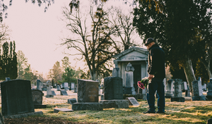 man holding flowers at a grave