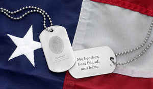 personalized stainless steel dog tag necklaces engraved with fingerprint and inscription laying on American flag